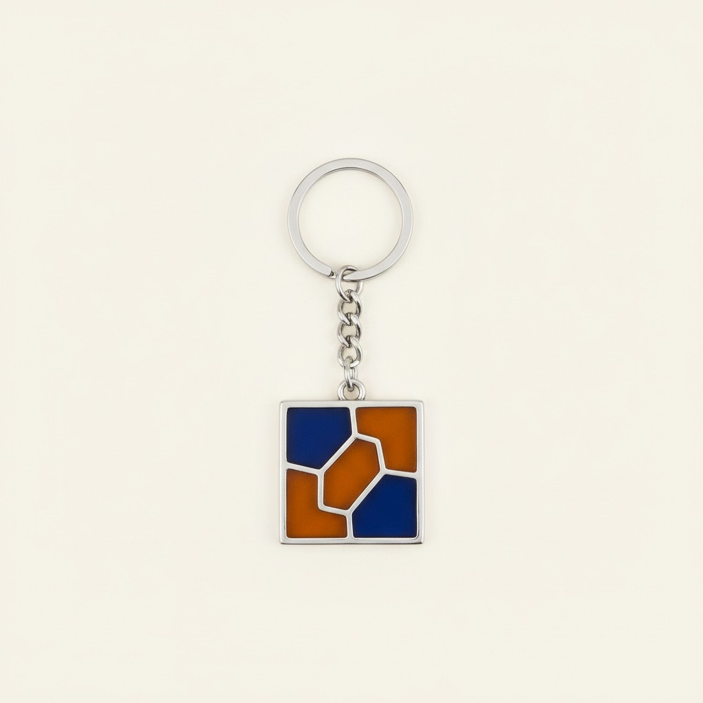 Abstract Tile Keyring — A square charm divided into cobalt and amber non-text geometric blocks.